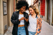© ManuPadilla - Diverse friends enjoying smartphone walking urban street