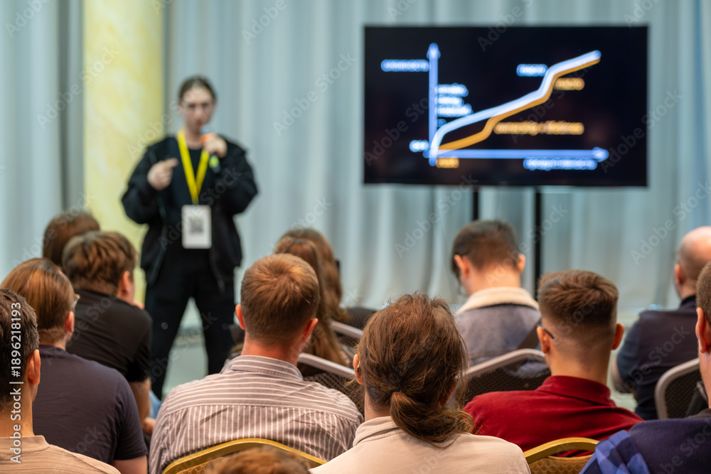 Presenter Using Yellow Note Presenter explains data trends to attentive audience beside large ...