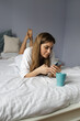 © SISMIZ - Woman Using Smartphone While Relaxing in Bed at Home