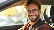 © mila103 - Smiling caucasian young male driver with curly hair and glasses enjoying a sunny day.