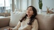 © LimeSky - Image of a pleasant young girl sitting on a couch with her eyes closed, dressed in a sweater, in a contemporary apartment