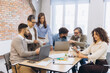 © anatoliycherkas - Diverse business professionals collaborating in office meeting, planning strategy using laptops and tablet for corporate teamwork
