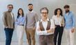 © anatoliycherkas - Mature business leader woman with diverse professional team smiling, standing in office, demonstrating teamwork and success