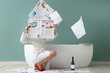 © Pixel-Shot - Legs of woman with many newspapers and champagne bottle sitting near bathtub against blue wall