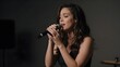 © Dmitry Kovalenko - Beautiful female singer performing emotionally in a dark minimalist studio, soft dramatic lighting highlighting expression and hands, symbolizing music, creativity, and inspiration.