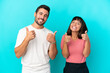 © luismolinero - Young couple isolated on blue background giving a thumbs up gesture with both hands and smiling