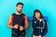 © luismolinero - Young mountaineer couple with a big backpack isolated on blue background with surprise and shocked facial expression