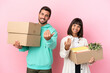 © luismolinero - young beauty couple moving in new home among boxes isolated on pink background inviting to come with hand. Happy that you came