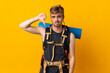 © luismolinero - Young mountaineer man with a big backpack isolated on yellow background showing thumb down with negative expression