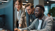 © Jhati - Three colleagues are gathered around a computer in a modern office setting looking at data