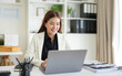 © wattana - Professional businesswoman working on a laptop at a modern office desk.