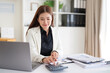 © wattana - Professional accountant working at a desk using a calculator and laptop while reviewing financial documents at desk.