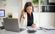 © wattana - Focused female accountant calculating numbers with a calculator beside a laptop and reports at a modern office.