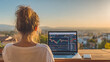 © Thawatchai - Female trader working on laptop with stock chart outdoor remote work sunset view freelance lifestyle concentration