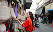 © Parichat - Young woman shopping for handmade bags at street market in Thailand