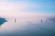© Bits and Splits - Foggy winter scene of the Danube river at dawn, featuring still water, pale sky, bridge remains, and peaceful atmospheric mood with copy space.