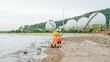 © ultramansk - Environmental scientists in PPE conduct water testing near an LNG terminal. They use a portable analyzer and laptop to monitor pollution levels at the coastal refinery.