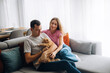 © verona_studio - Couple sits on couch with a cat in a cozy living room during a sunny afternoon