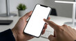 © PixelOriel - Man hands holding smartphone with blank screen and finger touching screen at office desk
