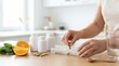 © Bay - Sorting nutritional supplements on kitchen counter with orange and spinach nearby in bright room