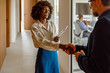 © Moon Safari - Cheerful mid adult businesswoman shaking hands and welcoming businessman in office during business meeting
