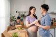 © Kawee - Asian young pregnant wife drinking a glass of milk with husband.