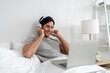 © Kawee - Asian young man using laptop device and listen to music with headphones.