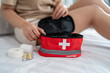 © Kawee - Close up of woman preparing a first aid kit after getting up from bed.