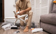 © Aboltin - Person assembles armchair at home, holding wheels and tools while preparing parts for installation. DIY concept, flat pack furniture and home improvement.