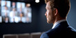© perfectlab - Side view of a businessman in a suit attending a virtual meeting with multiple participants displayed on a screen in a dark room