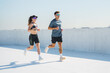 © muse studio - Young adults run on a rooftop in bright sunlight while enjoying their active lifestyle together