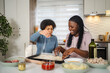 © Jelena - Two women preparing pizza dough in home kitchen
