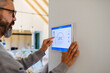 © Halfpoint - Man using smart home control panel.