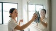 © Dmitry - Woman cleaning mirror with cloth in modern bathroom interior