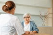 © Юлия Завалишина - Female doctor examining older senior woman in doctor office or at home. Old woman lady patient and doctor have consultation in hospital room. Medicine healthcare medical checkup. Visit to doctor