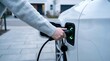 © Pixel Spark - Hand charging white electric car at home station