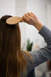 © Zoran Jesic - Woman brushing long brown hair with wooden brush