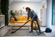 © Zoran Jesic - Woman vacuuming living room rug for clean home