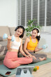 © Nuttapong punna - Two women exercising at home with dumbbells, yoga mat and headphones. Digital workout, fitness lifestyle, wellness and healthy living