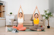 © Nuttapong punna - Two women practicing yoga and meditation at home with yoga mat and tablet. Wellness, mindfulness, home workout and healthy lifestyle concept with online fitness class.