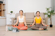 © Nuttapong punna - Two women practicing yoga and meditation at home with yoga mat and tablet. Wellness, mindfulness, home workout and healthy lifestyle concept with online fitness class.