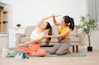 © Nuttapong punna - Two women practicing yoga at home with a personal trainer. Indoor fitness workout, stretching and wellness lifestyle using online guidance