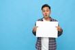 © ArvStd - Young asian man standing holding white blank board, for advertising, surprised facial expression, isolated blue background.