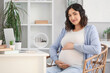 © Pixel-Shot - Young pregnant woman working at table in office