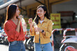 © Phimwilai - Young asian women communicating while drinking water outdoors