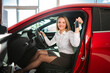 © Jelena - Happy woman holding new car keys in dealership