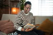 © Jelena - Woman enjoying reading book on couch at home