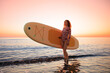 © Igor Yaruta - Young woman standing on beach with paddle sup boards during summer vacation