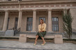 © svetograph - Woman, Bench, Building: A woman in a yellow top and green skirt sits on a stone bench in front of a building with columns.