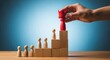 © Valery - Hand placing red leader figure with crown on wooden blocks showing leadership hierarchy success and team growth